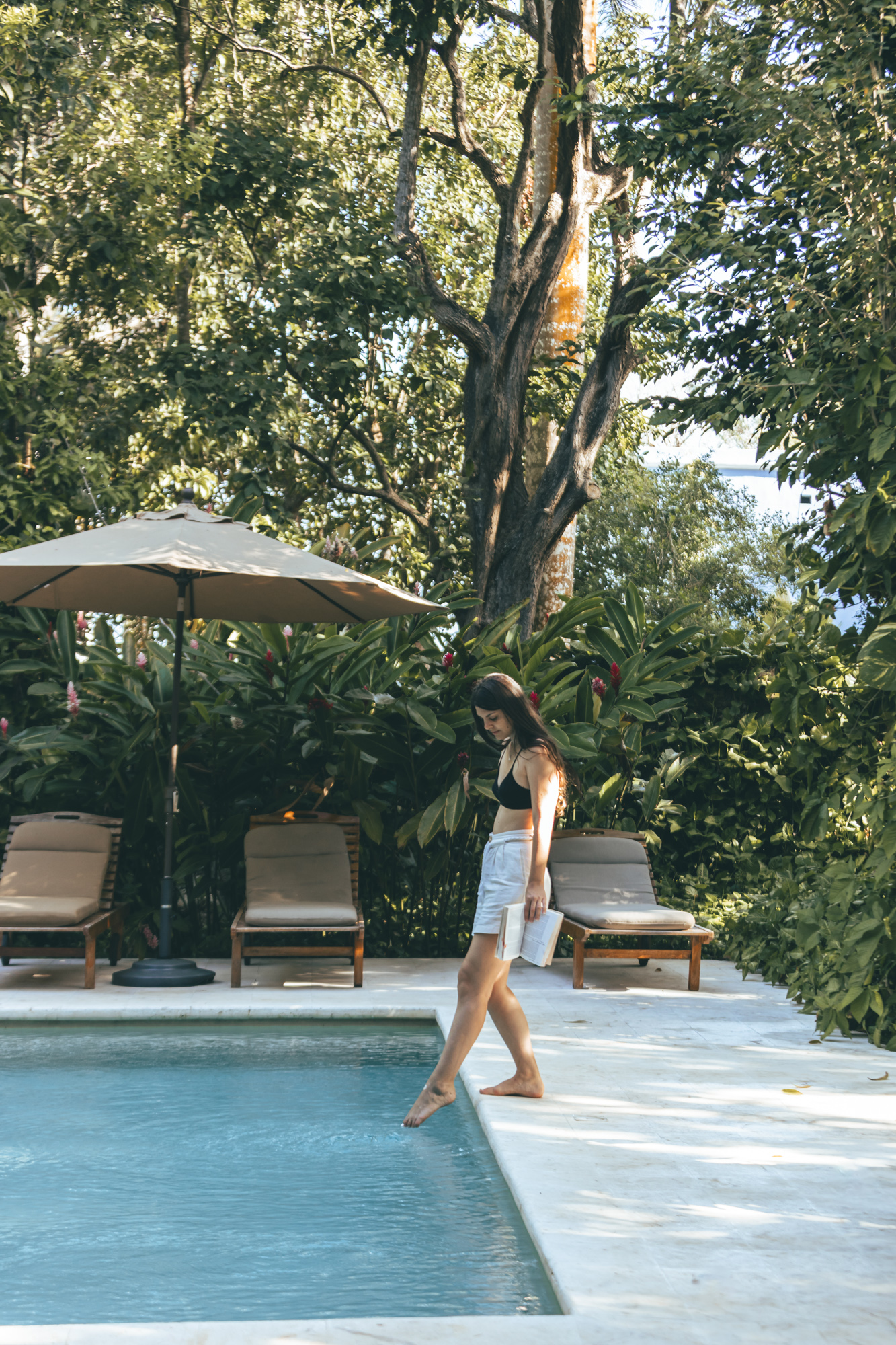 Woman walking by the serene poolside at Hacienda San Antonio Millet in Merida, Mexico