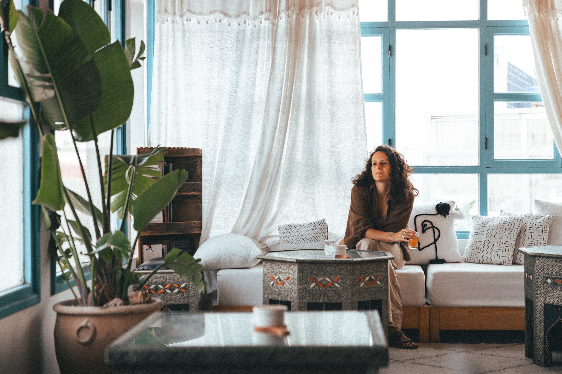 Woman relaxing in cozy lounge at Riad Kafila, Essaouira, Morocco