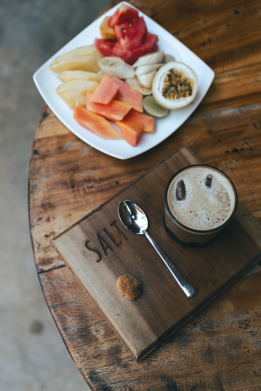 Fresh tropical fruit platter and coffee on a wooden table at Salt House Hotel near Hiriketiya Beach, Sri Lanka