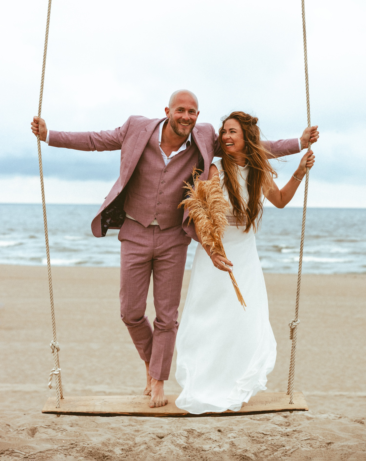 A joyful couple on a beach swing, with the sea and sand creating a perfect backdrop