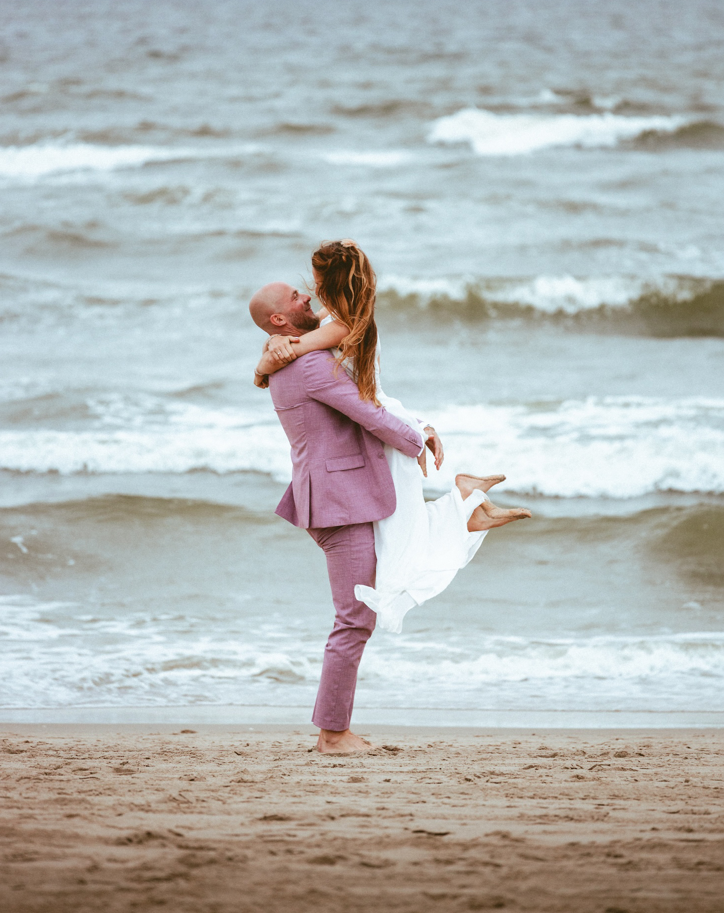 A romantic embrace by the waves, as a couple shares a moment of pure joy on the beach