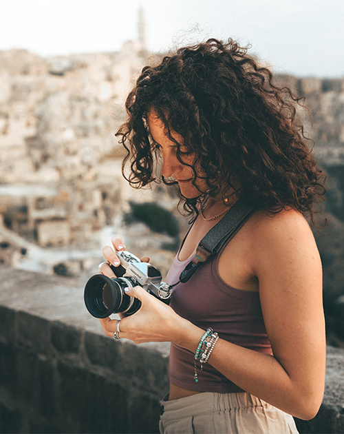 Photographer focusing her lens on a breathtaking cityscape, showcasing the potential of pre-owned cameras from MPB in creating stunning visuals