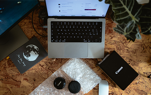 A photographer's workspace featuring a laptop, second-hand camera lenses, and a tablet, all sourced from MPB for a professional photography setup