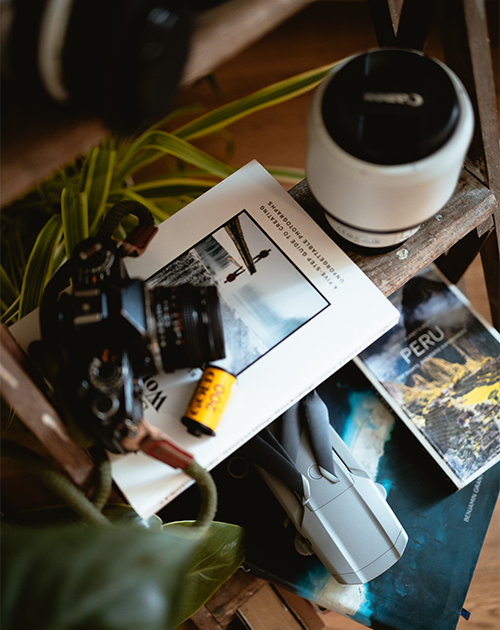 A carefully arranged photographer's corner with second-hand camera gear, lenses, and a photography magazine, promoting MPB's sustainable photography practice