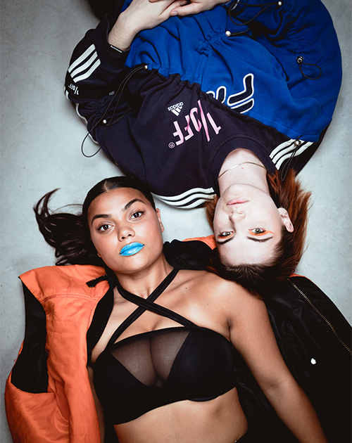 Overhead shot of two models lying on the ground, showcasing bold colors and fashion textures