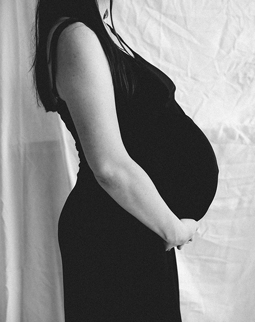 Contemplative side profile of a pregnant woman in a simple yet elegant setting