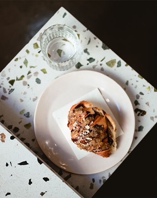 Gourmet pastry served on a chic terrazzo plate, accompanied by a clear glass of water