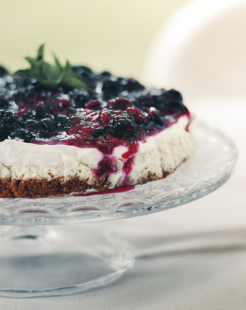 Creamy cheesecake with a vibrant berry topping on an elegant glass stand