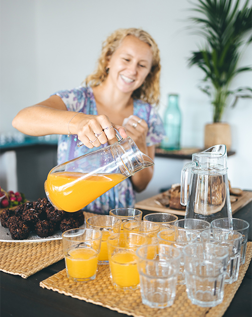 Maddie's refreshing start to a sunny day, pouring bright orange juice into glasses, echoing the vibrant energy of Fuerteventura's Surf & Yoga retreats