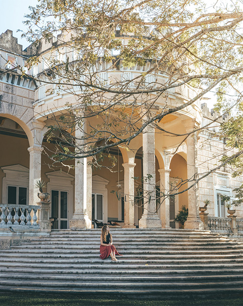 Elegant woman in a flowing dress seated on the grand stone staircase of Hacienda San Antonio Millet