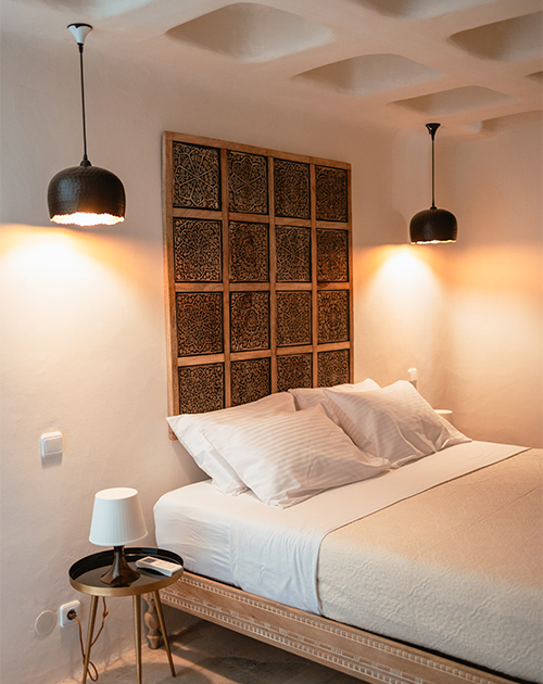 Cozy and inviting bedroom with ambient lighting and unique wall art in a Mykonos seaside house, depicting comfortable luxury