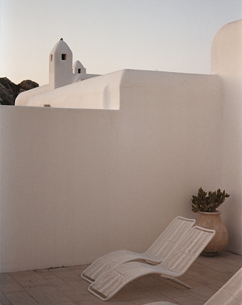 Relaxing outdoor lounge area with white sunbed and a peaceful sea view in Mykonos, reflecting the soulful retreat of the Aegean island