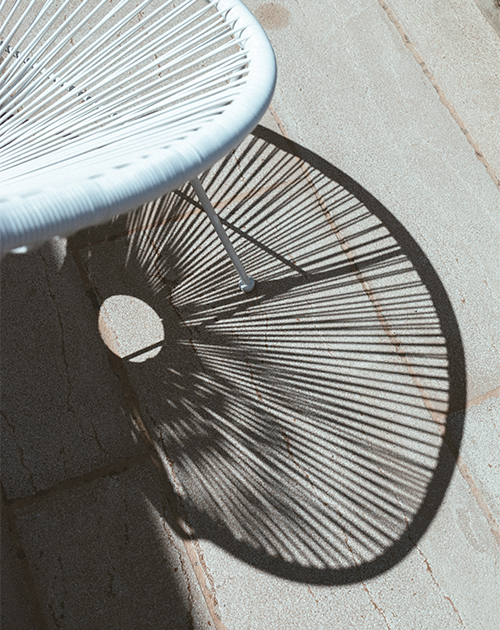 Artistic interplay of light and shadow from a terrace chair at a private Mykonos house, illustrating the simple elegance of the property