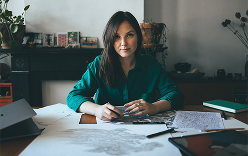 Rotterdam-based graphic artist Visnja at her desk with sketches and drawing tools, embodying creativity