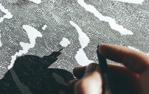 Close-up of artist Visnja's hand as she meticulously draws intricate patterns, a testament to her detail-oriented craftsmanship