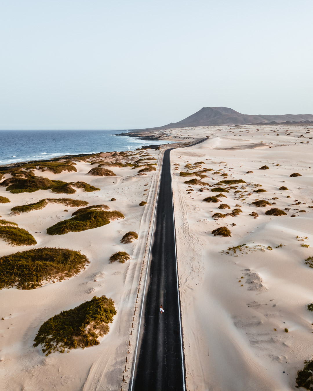 A solitary road slicing through the sandy desert landscape of Fuerteventura, Canary Islands