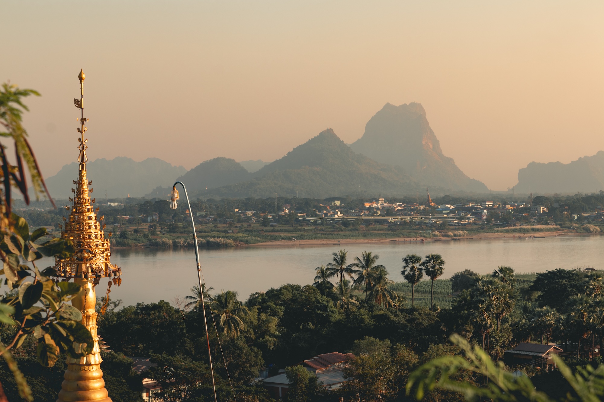 The serene Hpa-An region in Myanmar, showcasing the lush landscape with a golden pagoda overlooking the tranquil river.