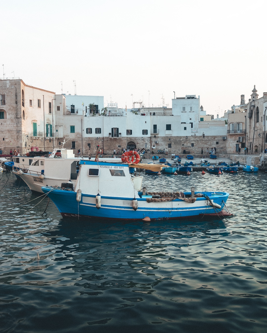 Colorful boats moored in the calm waters of Monopoli harbor in Italy