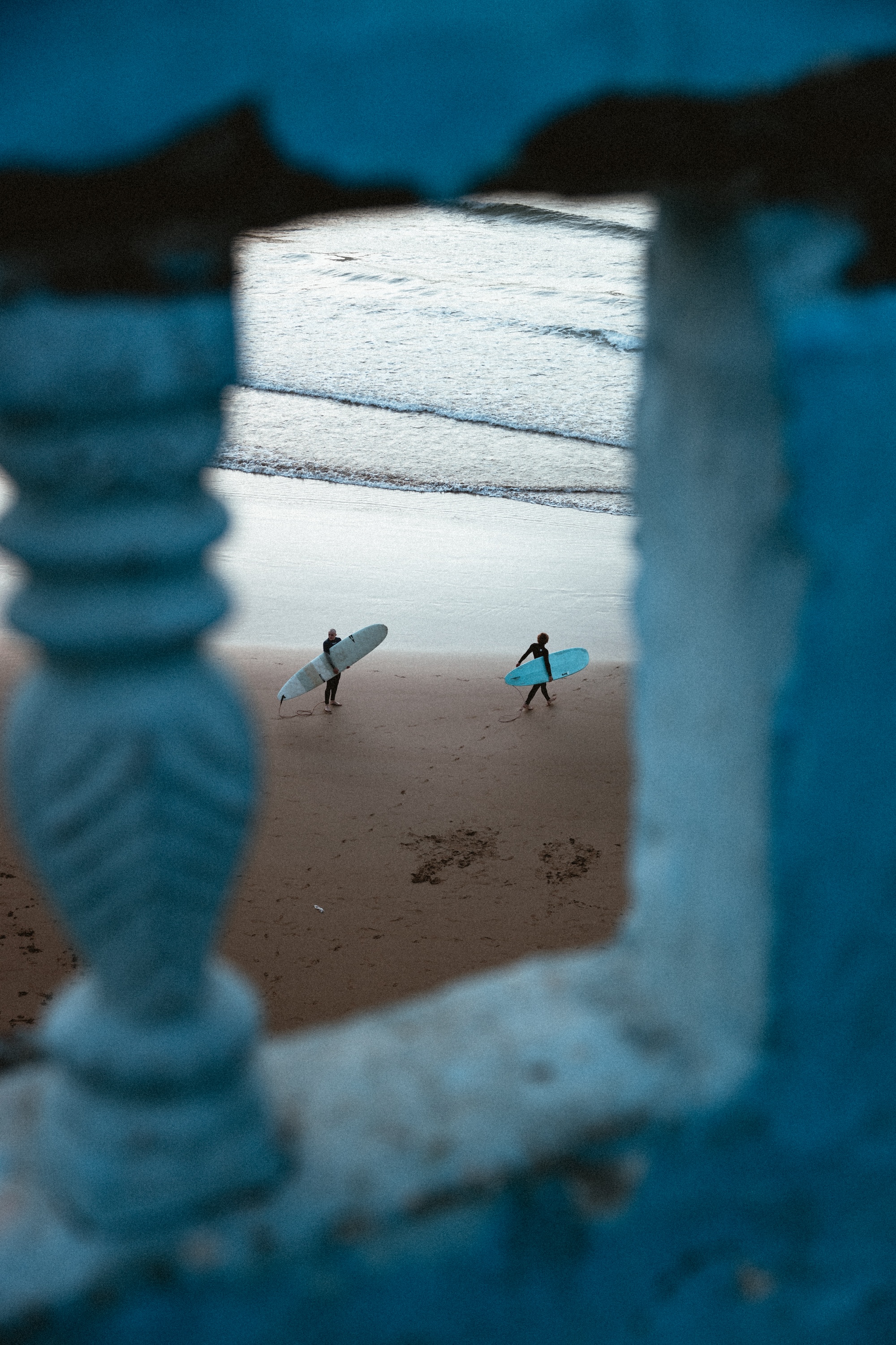 Two surfers with blue boards on the sandy beach of Imsouane, Morocco